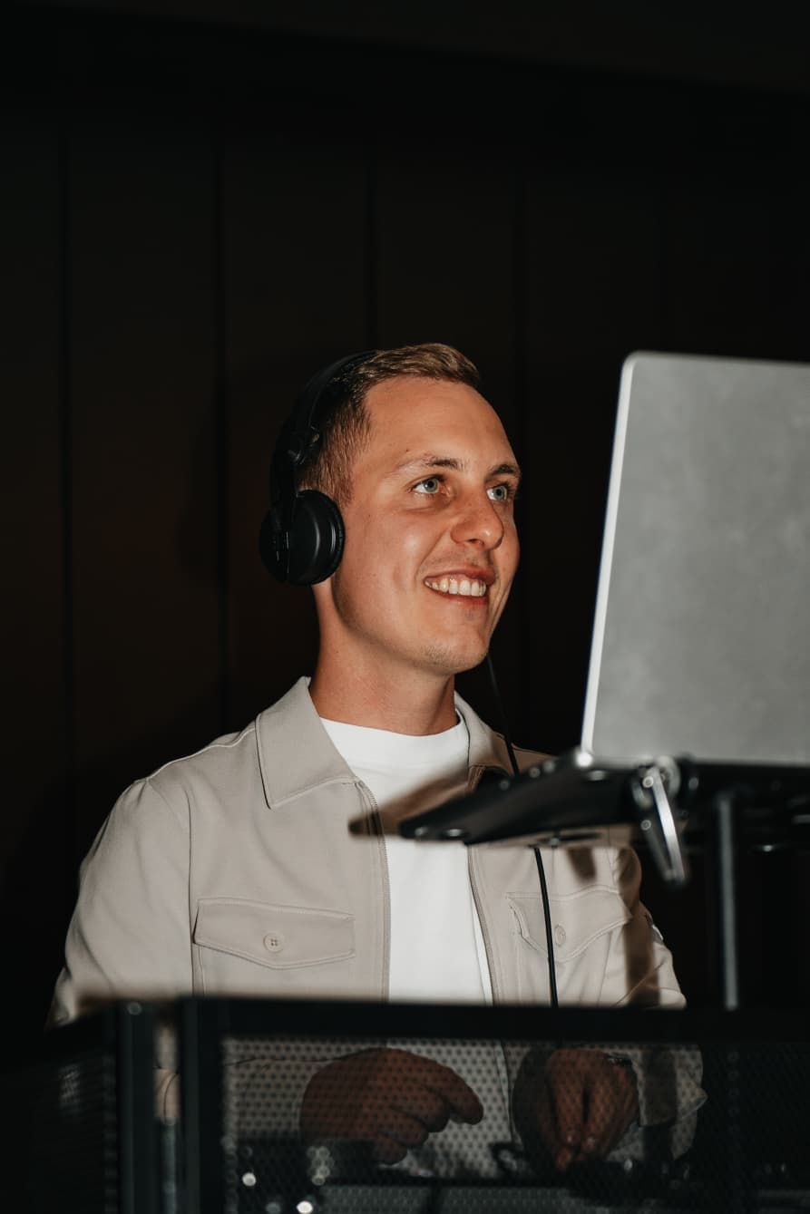 DJ Lukas lächelt mit Kopfhörern am DJ-Pult