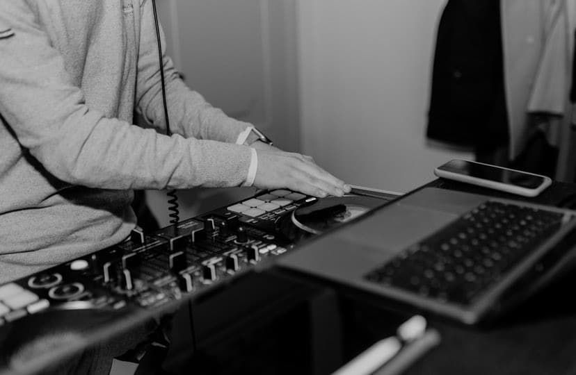 Hände eines DJs am Controller neben dem Laptop