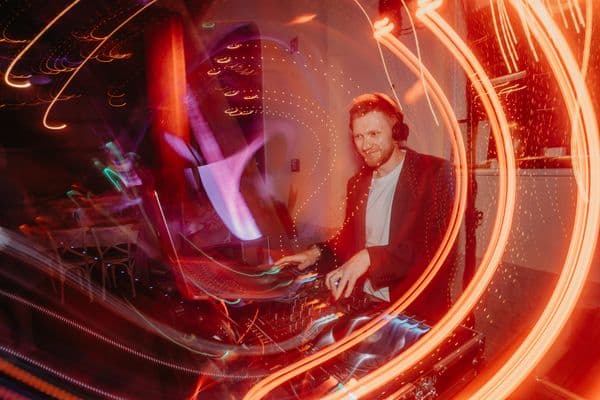 DJ am Pult, umgeben von leuchtenden Lichtspuren