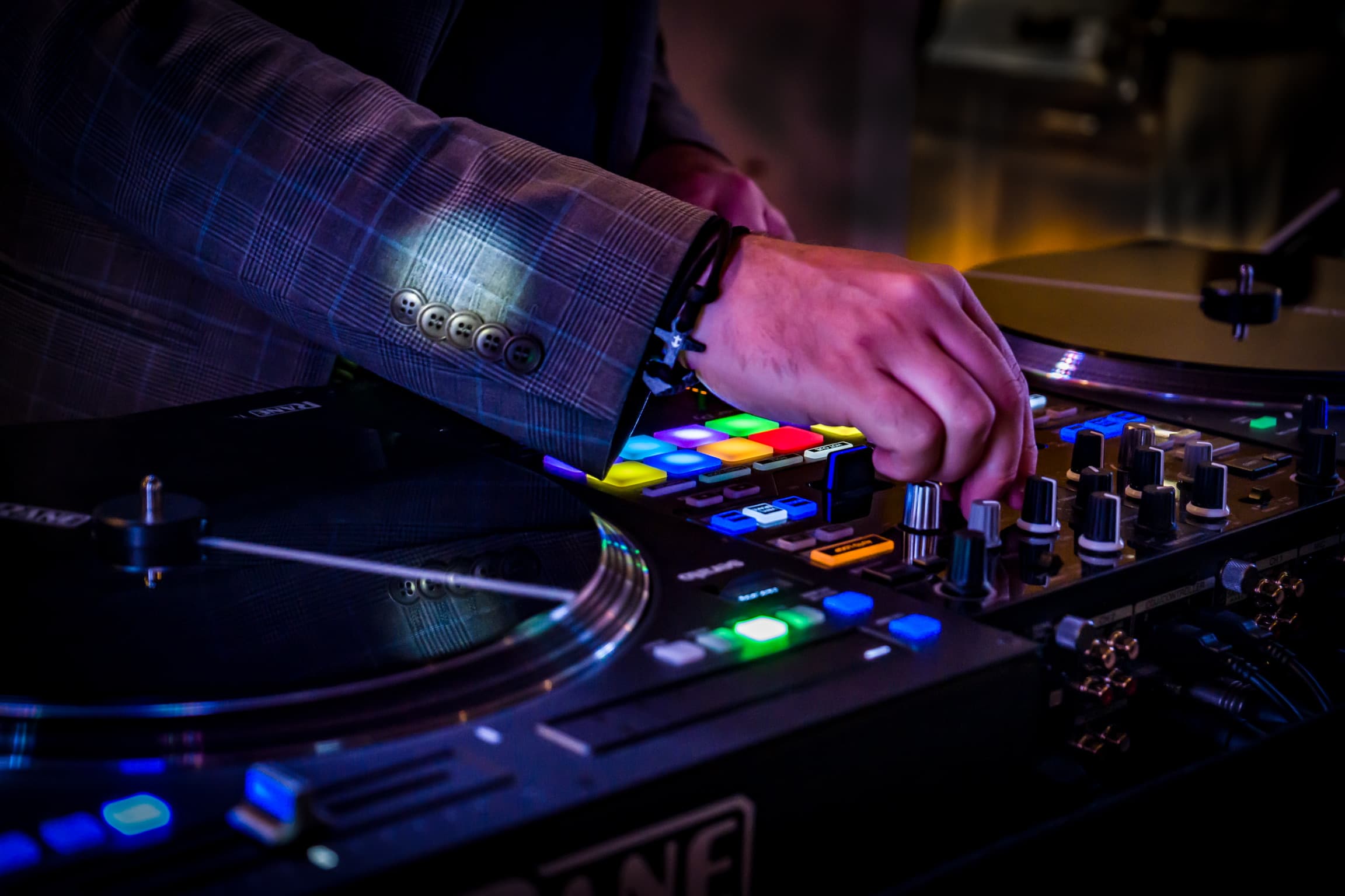 DJ-Hand am Mischpult mit bunter Beleuchtung