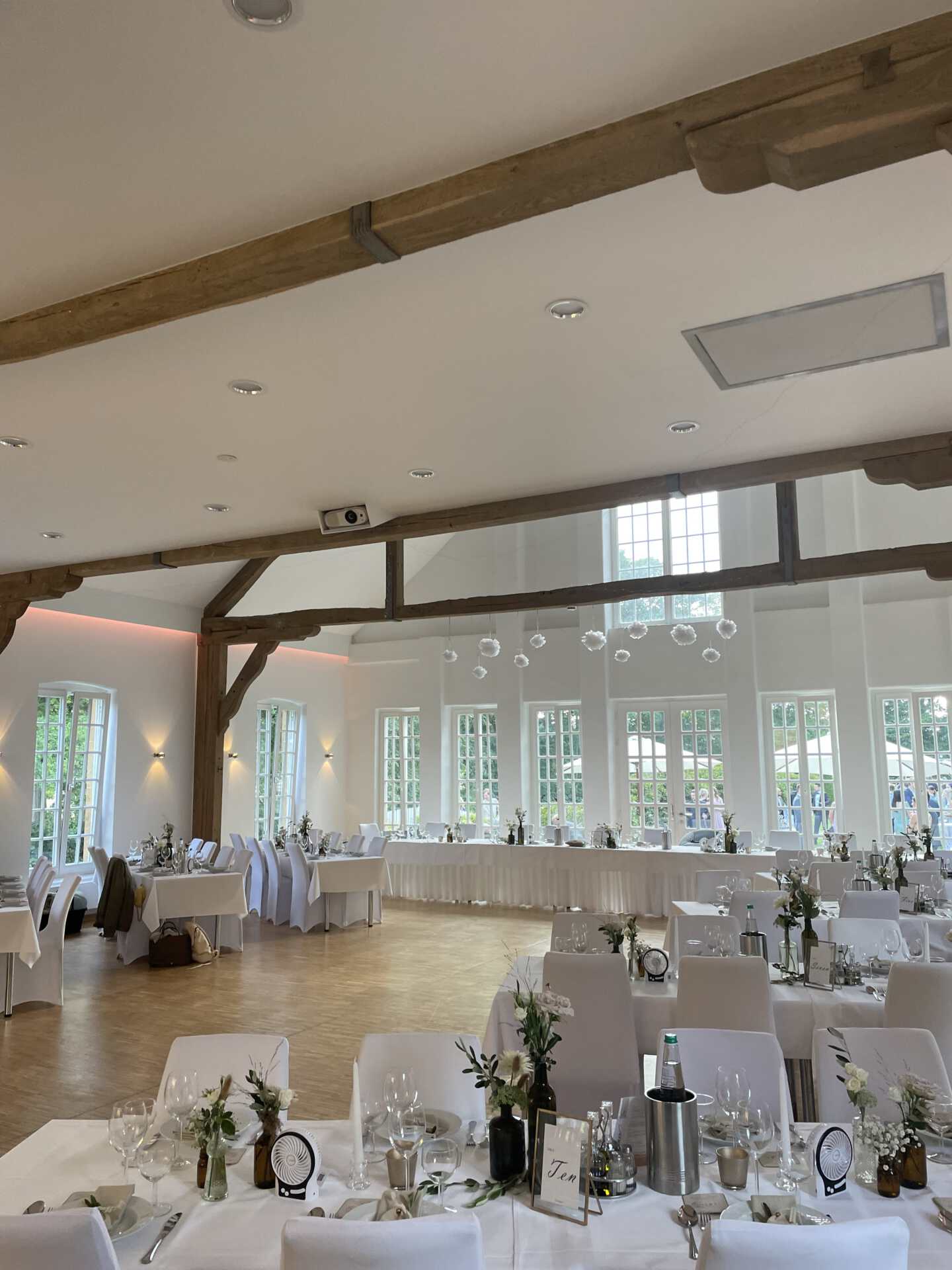 Heller Festsaal mit Holzbalken und gedeckten Tischen auf Schloss Holtfeld