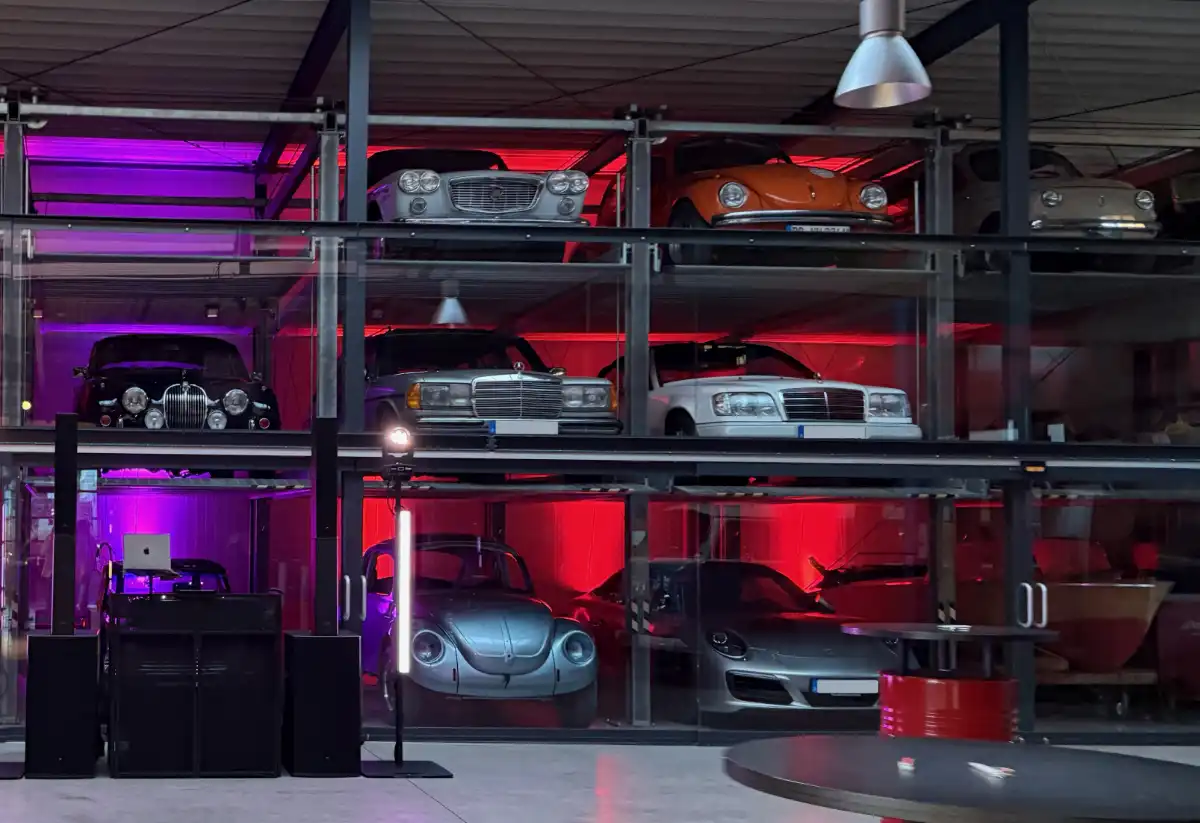 DJ-Setup von DJ Felix vor beleuchteten Oldtimern in der Oldtimergarage Paderborn