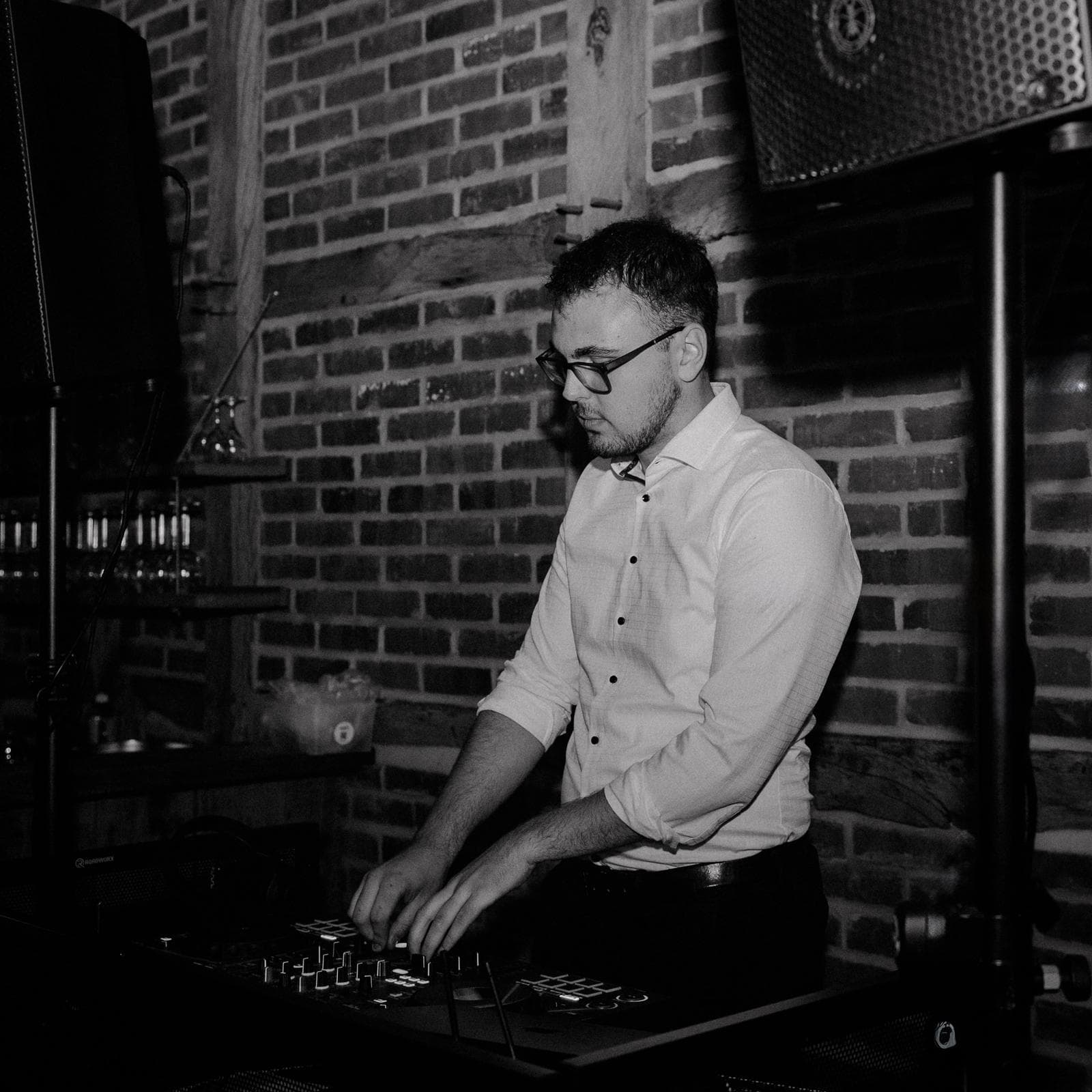DJ Jannik mixt an einem DJ-Pult vor einer Backsteinwand
